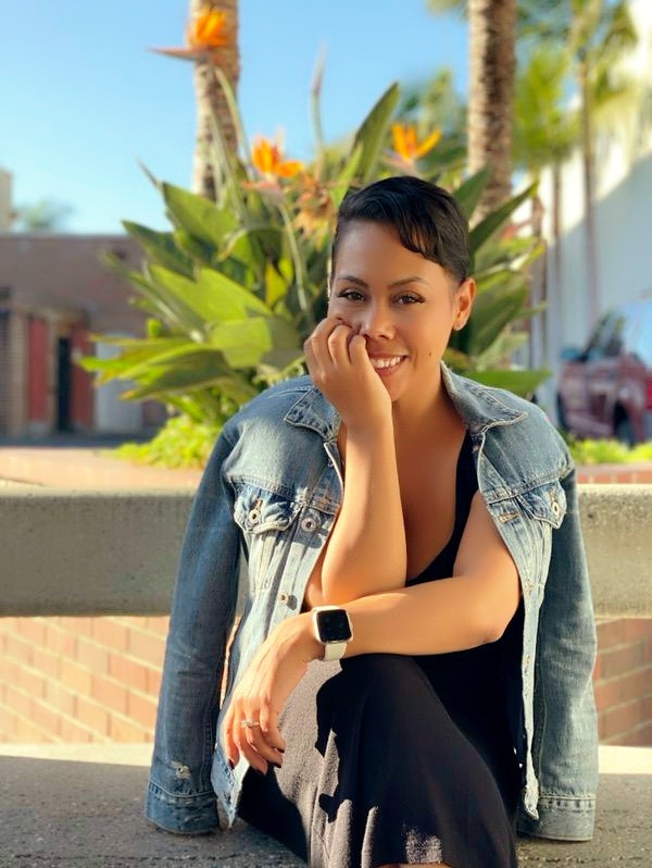 Tiana Jovana seated outdoors, smiling in a denim jacket